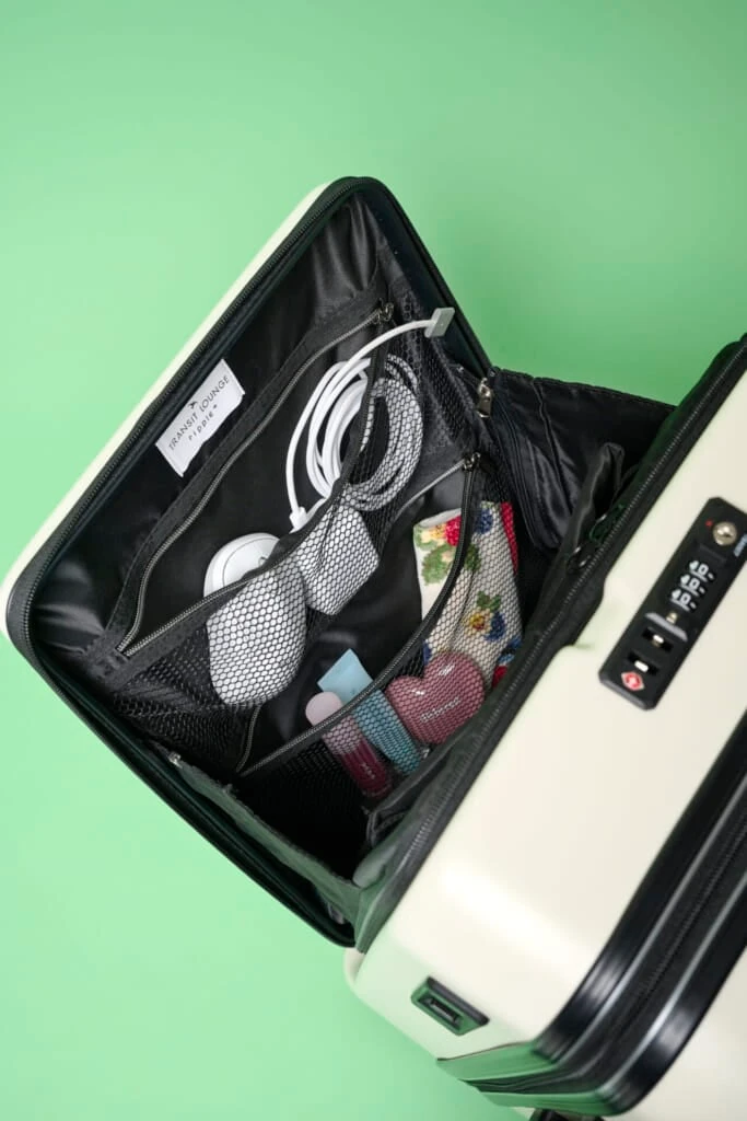 リップルプラスのスーツケースのフロントポケットを開け、充電器やマウスなどをネット型ポケットに入れた様子。