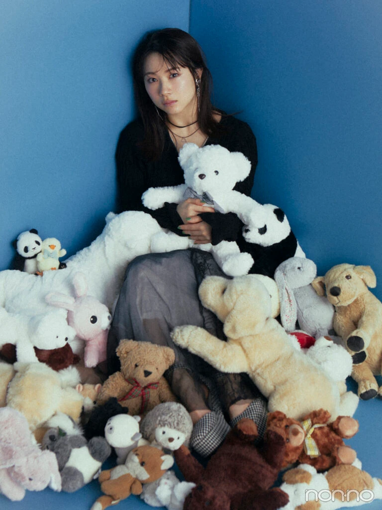 たくさんのぬいぐるみに囲まれ、くまのぬいぐるみを抱いて座っているモーニング娘。'24の石田亜佑美さん