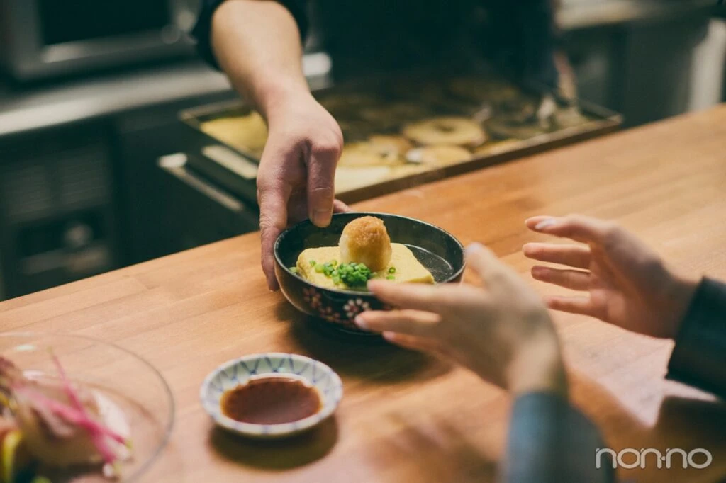 だし巻き卵が入った皿と店員の手元