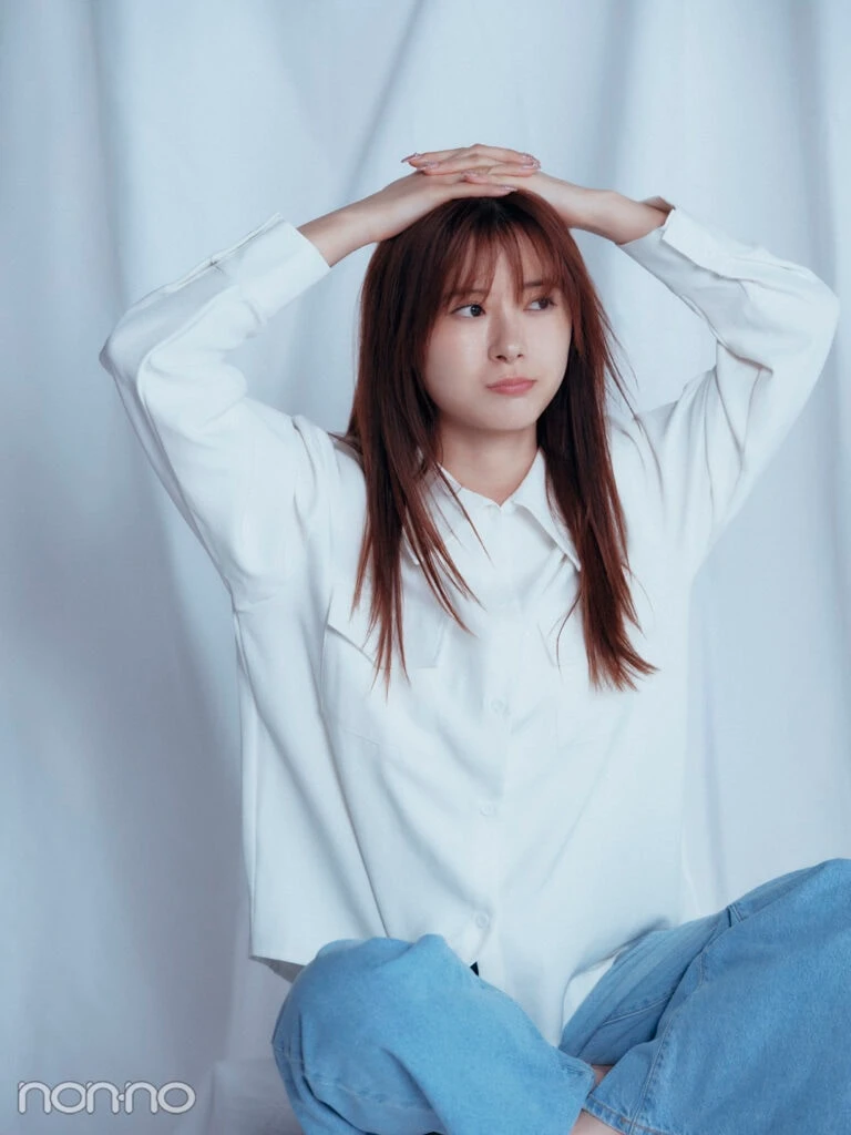白シャツにデニムというシンプルな装いで座り、頭に手を乗せたモーニング娘。’25の生田衣梨奈さん