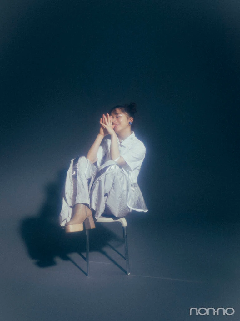 椅子の上に座り、笑顔で目を閉じる石田亜佑美さん
