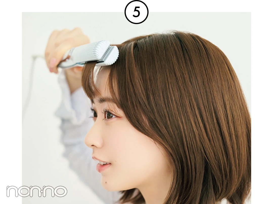 前髪全体をストレートアイロンではさむ女性