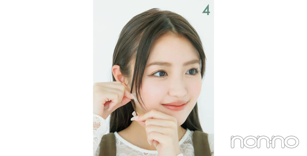 サイドに流した前髪の毛先をつまんでいる女性