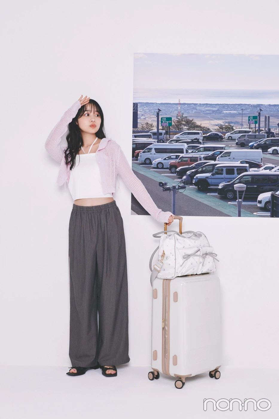 ピンクのカーデにグレーのスラックスを履いた林芽亜里