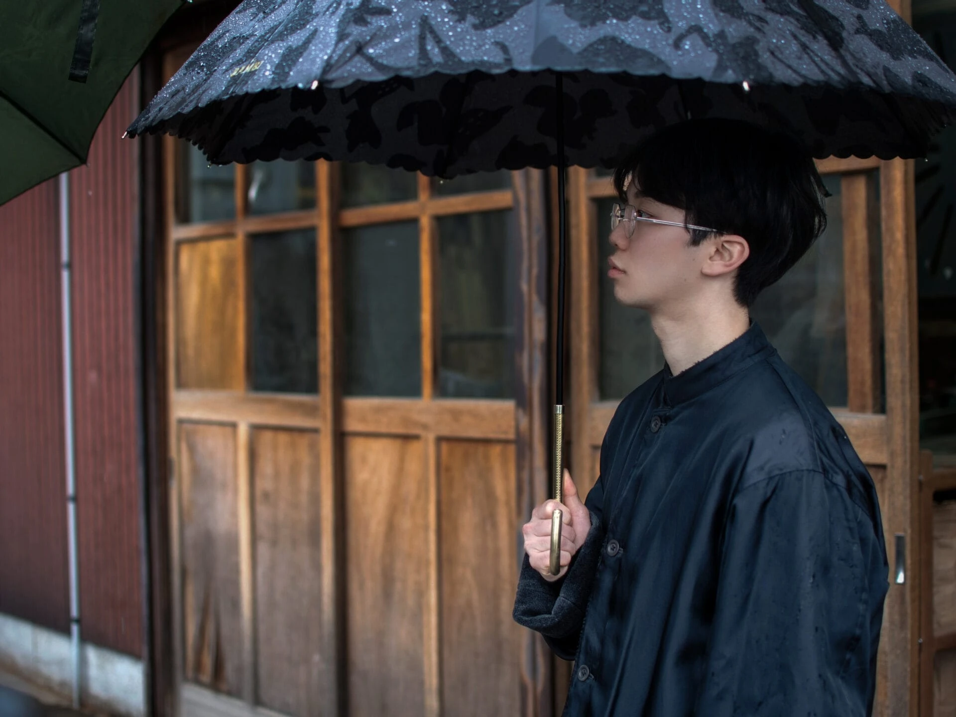 雨の中、傘をさす友野一希さんの横顔