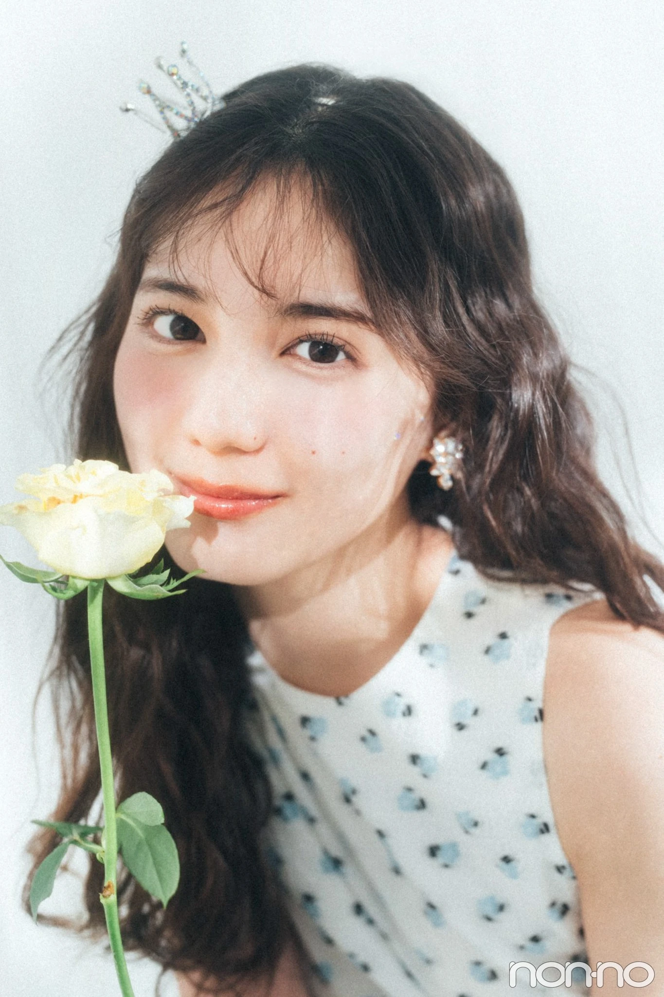 バラの花を持ってこちらを見る小坂菜緒
