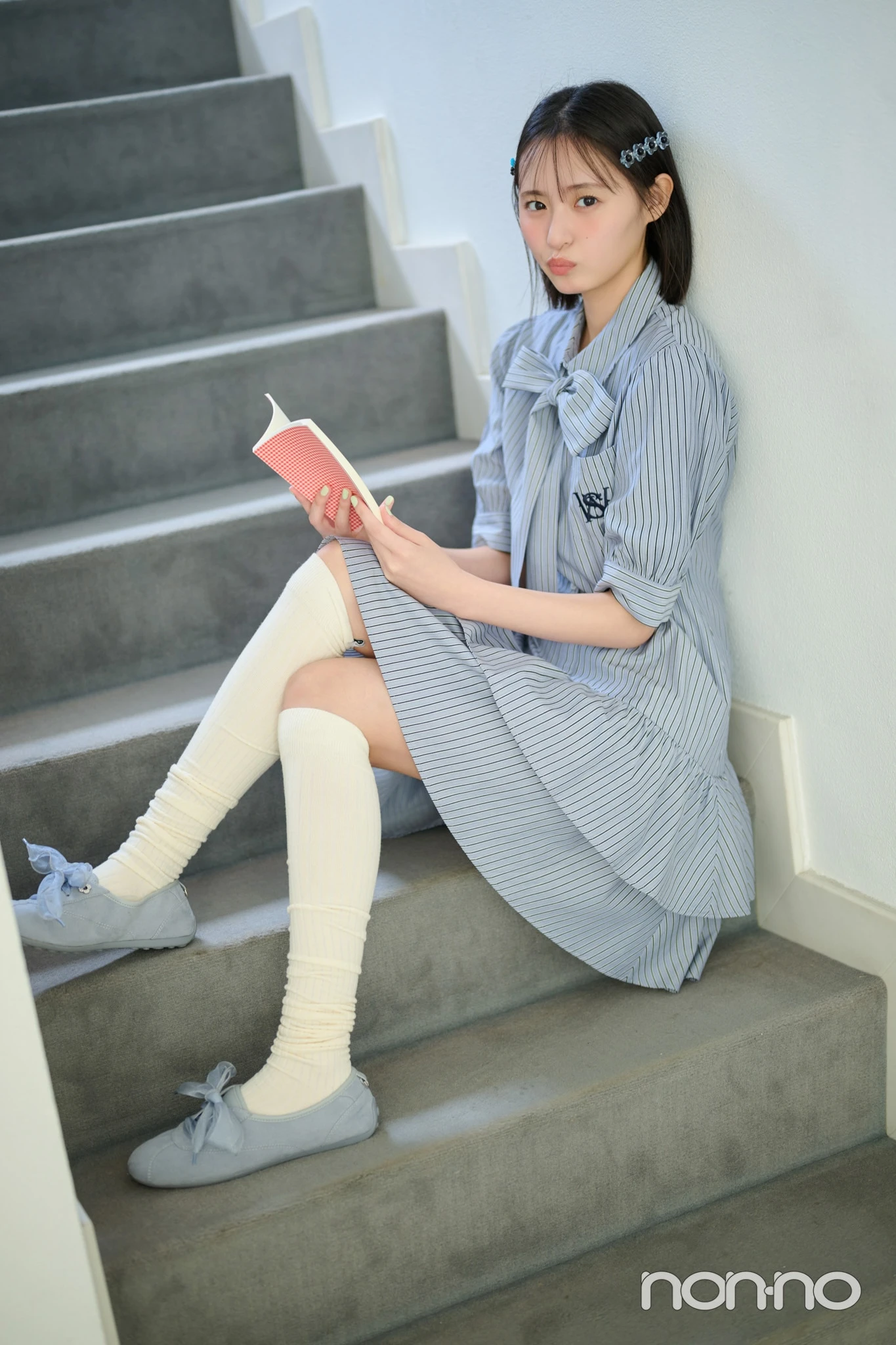 シャツワンピを着て階段で本を持つ遠藤さくら