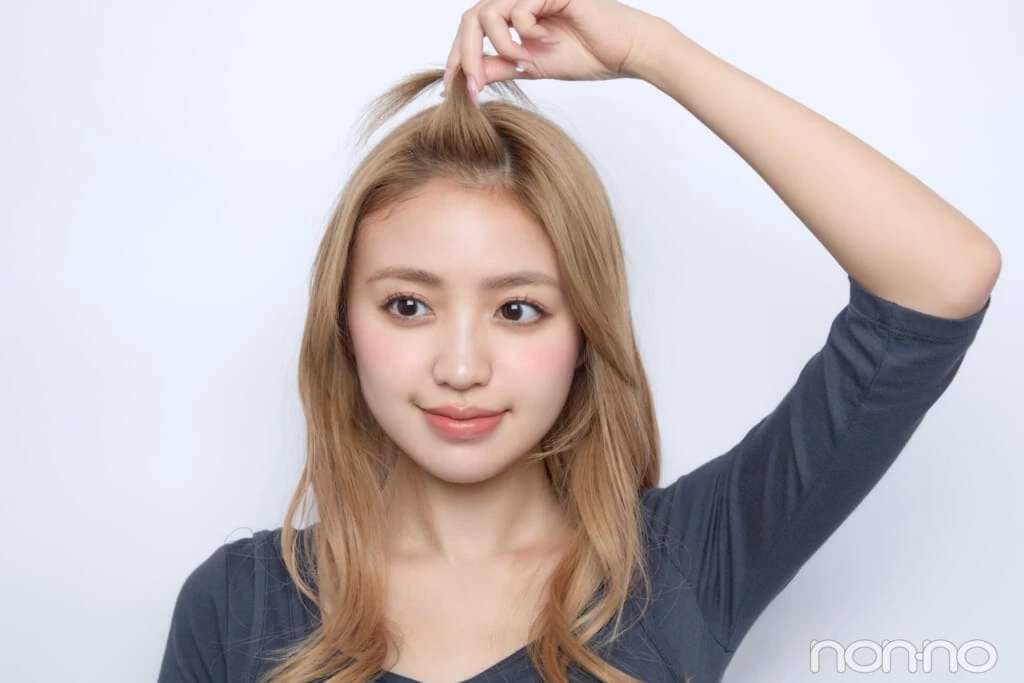 指で前髪を上にあげている女性