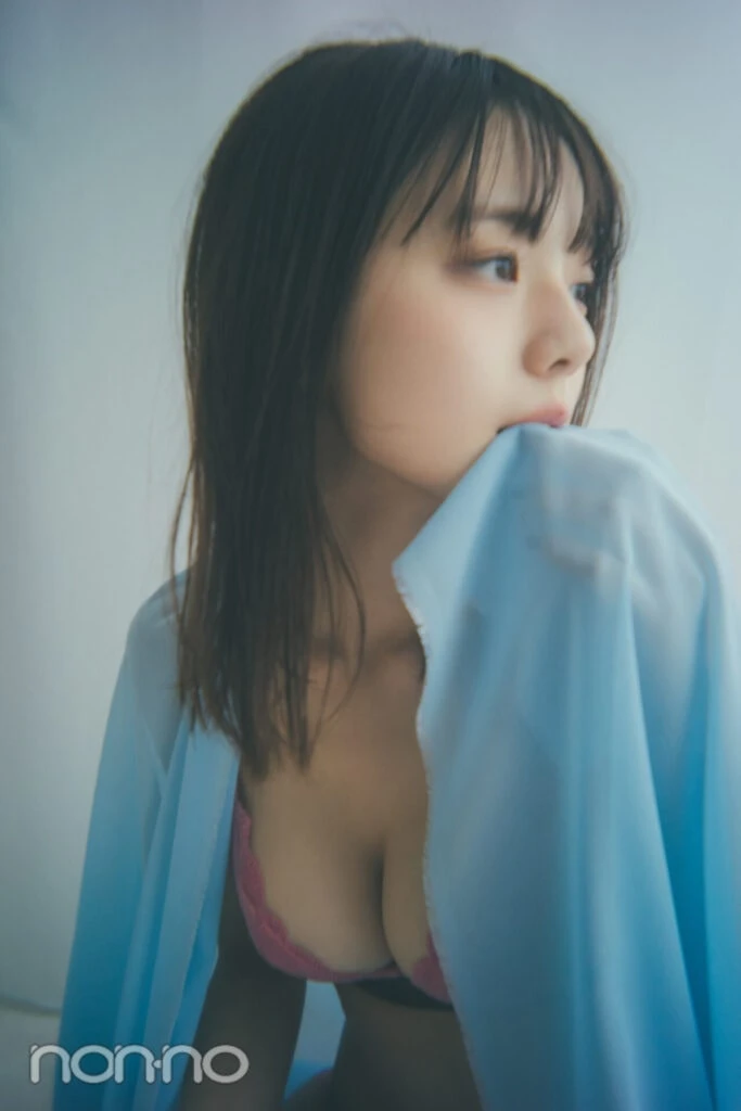 ピンクレースブラを着た菊地姫奈がブルーの布を咥えて座っているカット