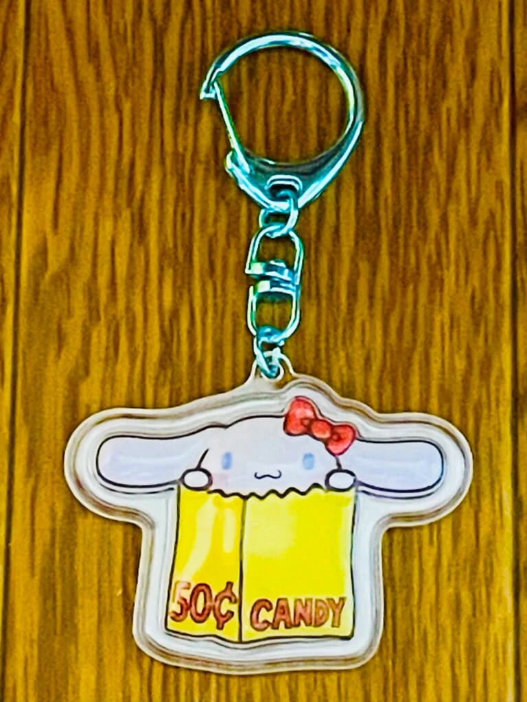 シナモンのキーホルダー。キティ展のロゴにちなんで、黄色い紙袋から顔を出すデザインとなっている。