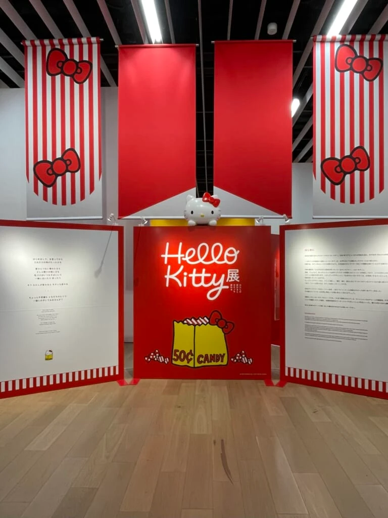ハローキティ展の最初のブース。キティ展のロゴと歴史が記載された看板が3つ並んでいる。