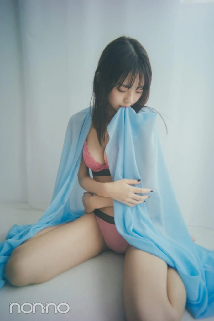 ピンクレースブラを着た菊地姫奈がブルーの布を咥えて下を向いているカット