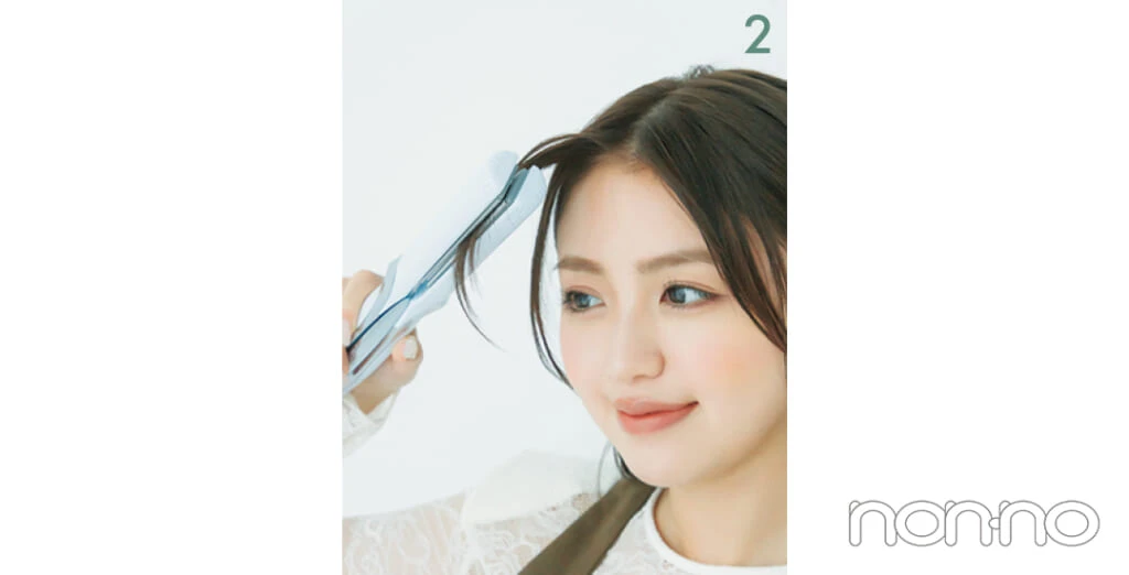 ストレートアイロンで前髪をはさんでいる女性