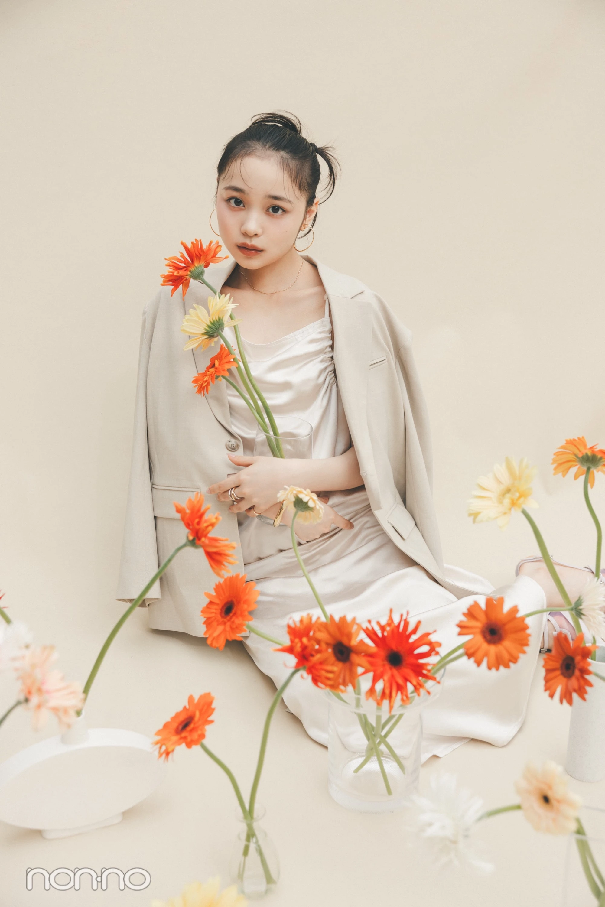林芽亜里が、花瓶に入ったガーベラを抱えているカット