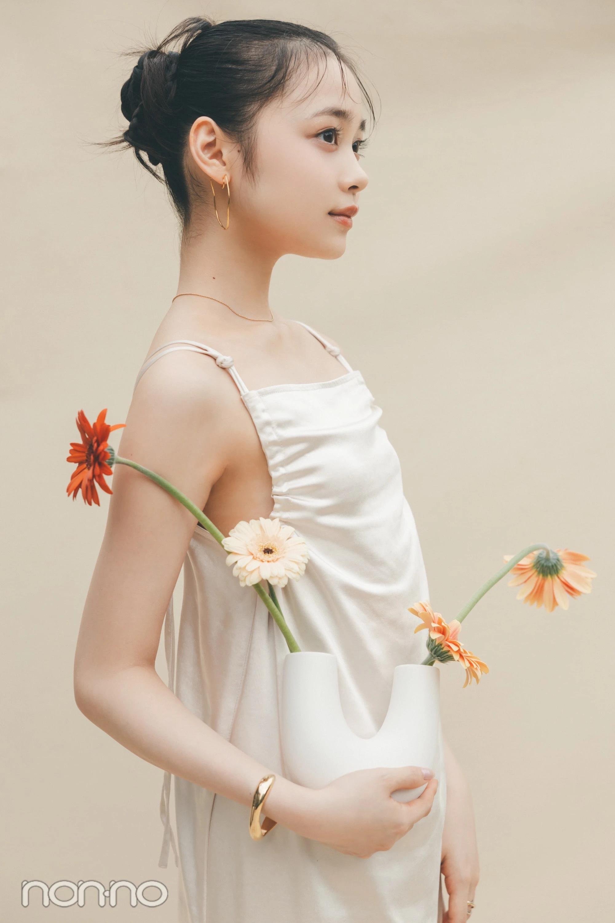 林芽亜里が、U字の花瓶に入ったガーベラを右手で持っているカット