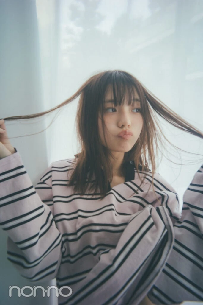 ボーダートップスを着て髪の毛をいじっている菊地姫奈