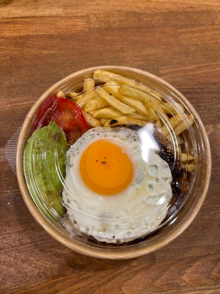 ポテトやアボカド、トマト、目玉焼きなどが入った器の写真