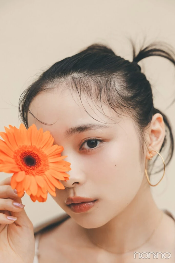 林芽亜里は、ガーベラで片目を隠しているカット