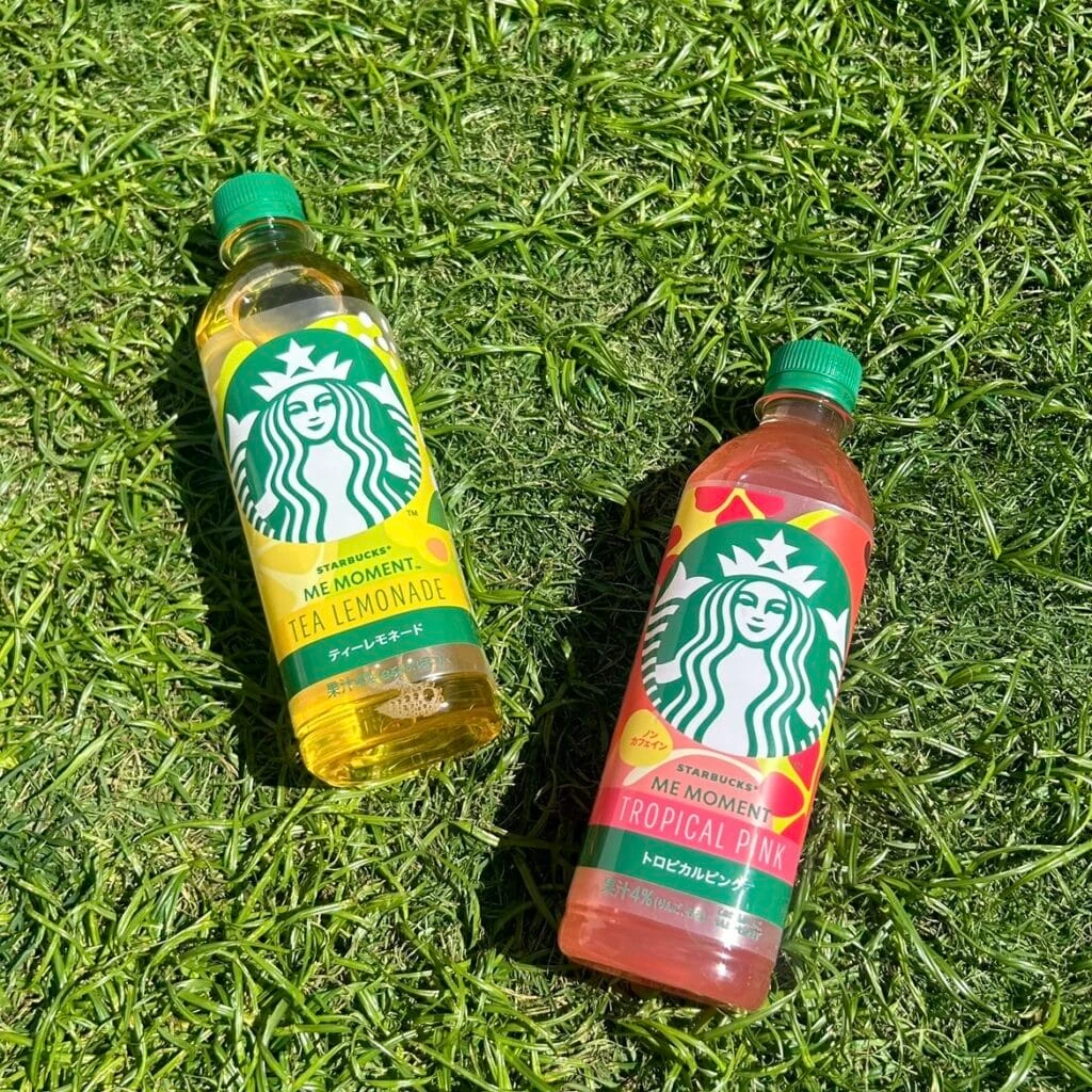 芝の上に置かれたスターバックス® ME MOMENT™ ティーレモネードと スターバックス® ME MOMENT™ トロピカルピンク™の写真