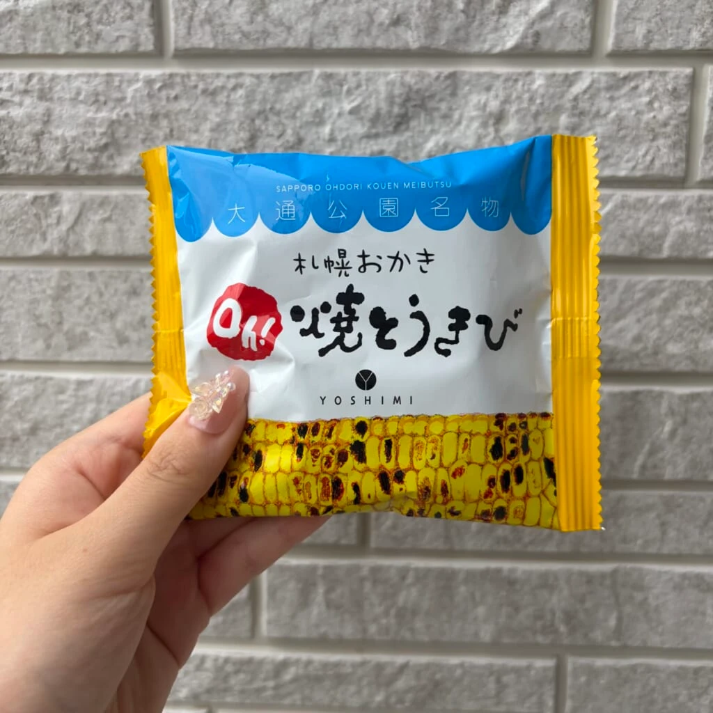 青と黄色の袋菓子を白壁の前で持つ