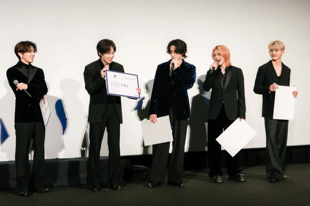 INIドキュメンタリー映画完成披露試写会でフリップを見せ談笑するメンバー