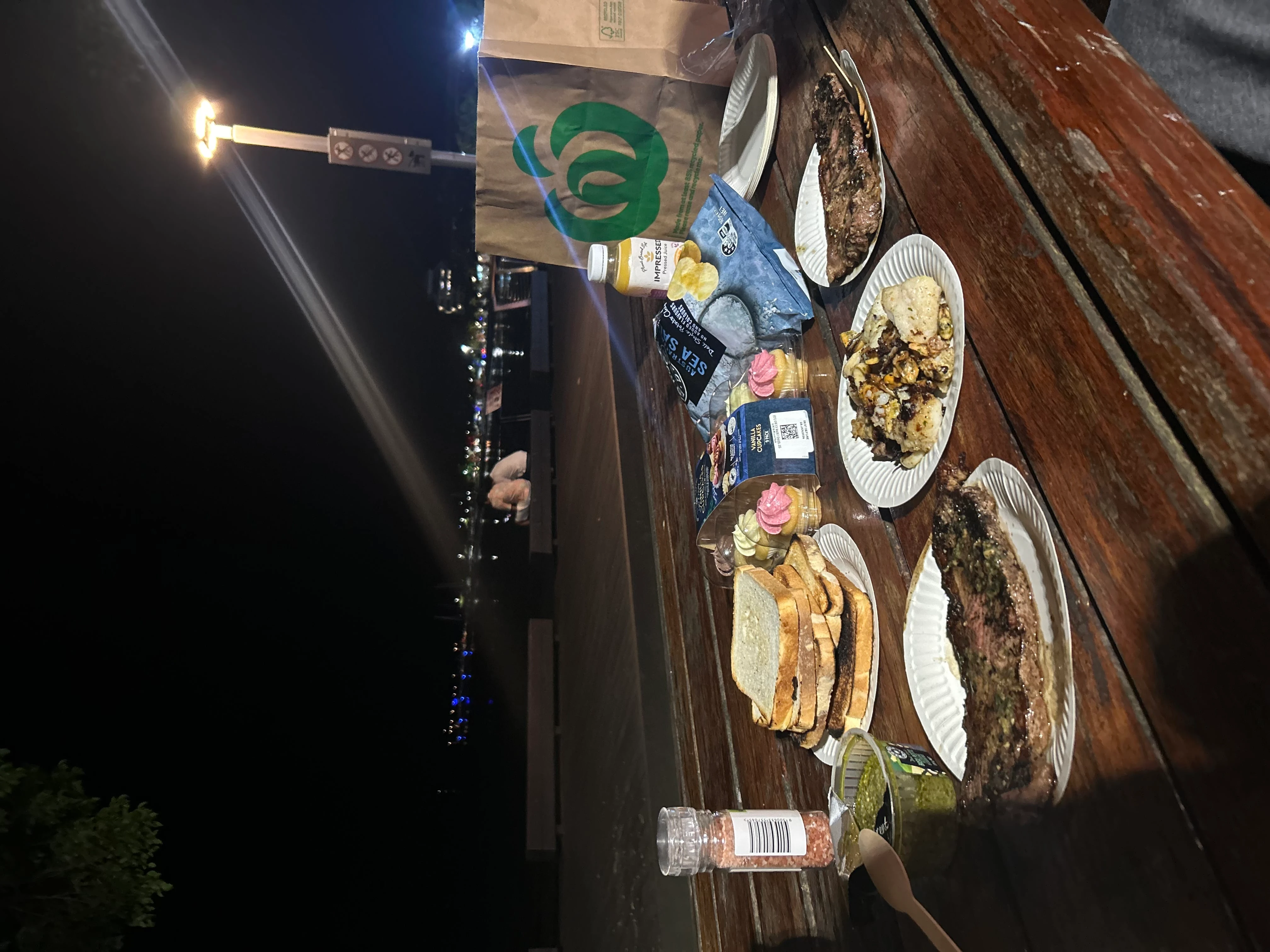 ビーチの前のベンチに料理を広げて食べる写真。