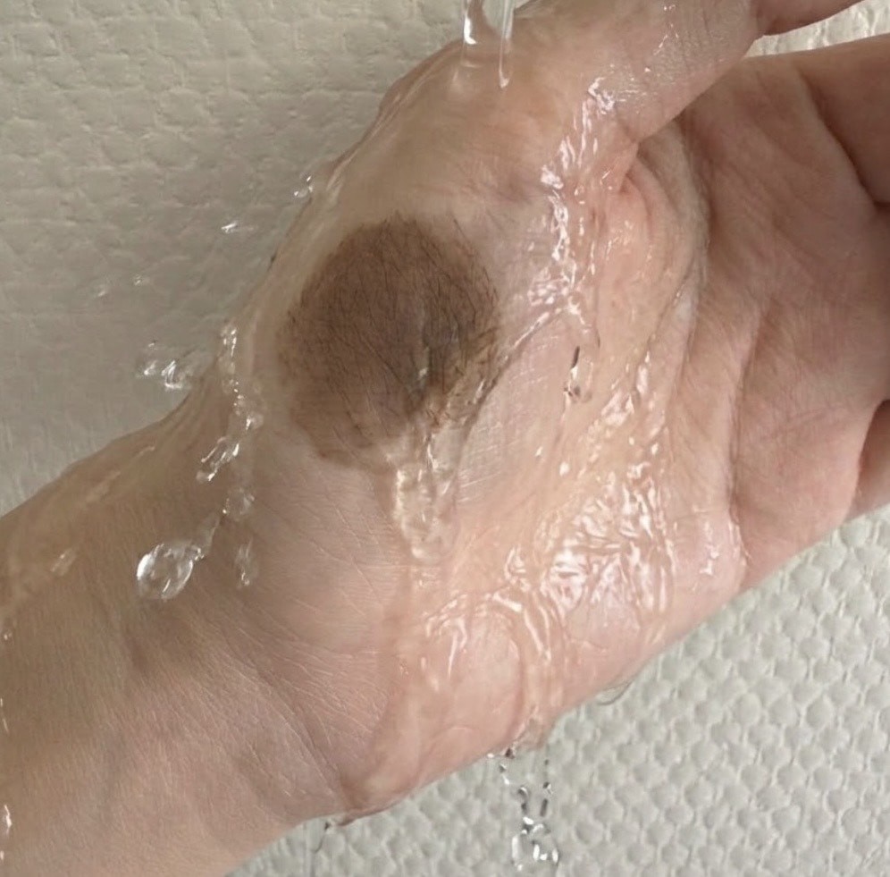 手の甲のティントに水を当てている様子