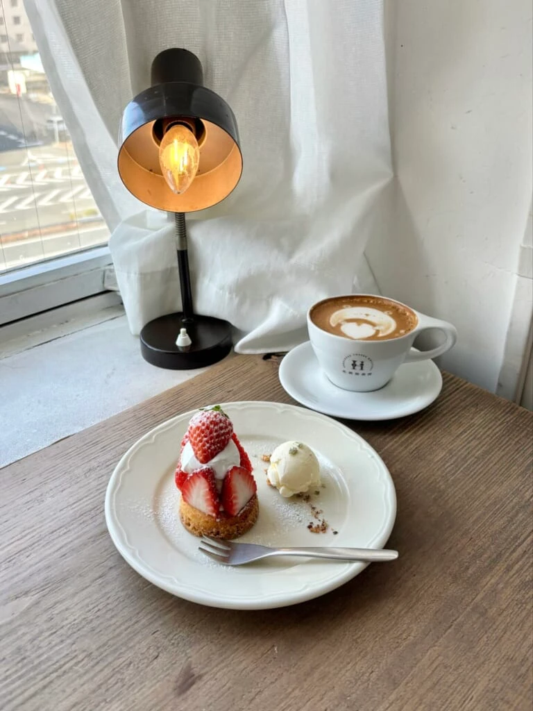 窓側のカウンター席でいちごのタルトとカフェラテ