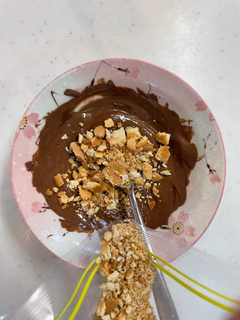 溶かしたチョコに砕いたクッキーを混ぜている