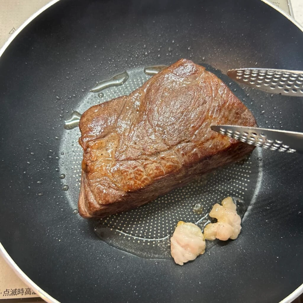 高温のフライパンで牛脂を使い塊肉の表面を焼き付ける工程