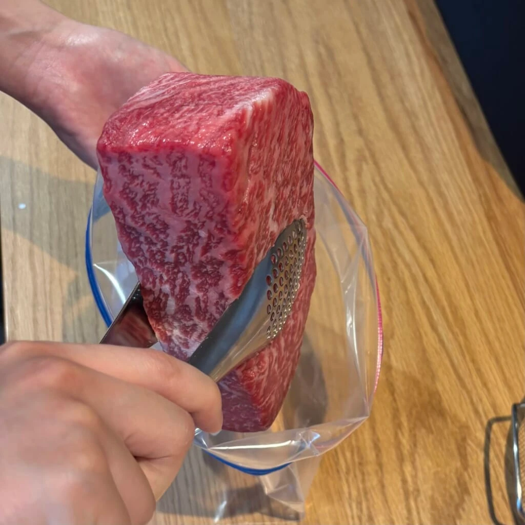 空気を抜きながら牛の塊肉を保存袋に入れる下準備