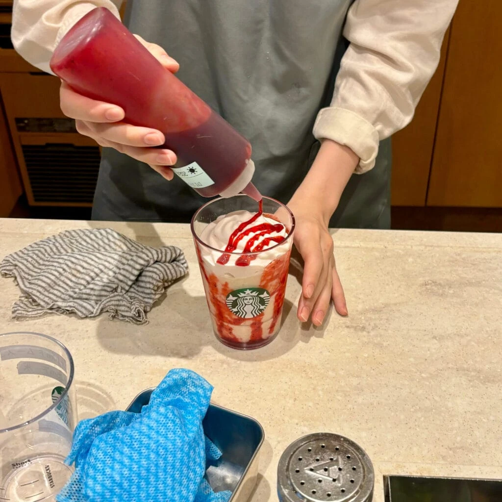 フラペチーノにストロベリーソースをトッピングする様子