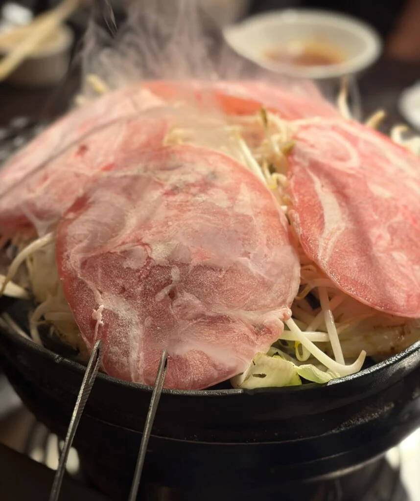 野菜を敷いた鍋でラム肉を焼いているところ