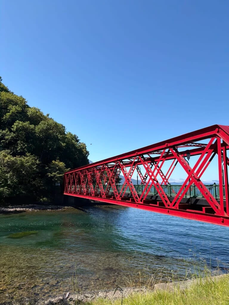 澄んだ水の上に架かる赤い鉄骨の橋