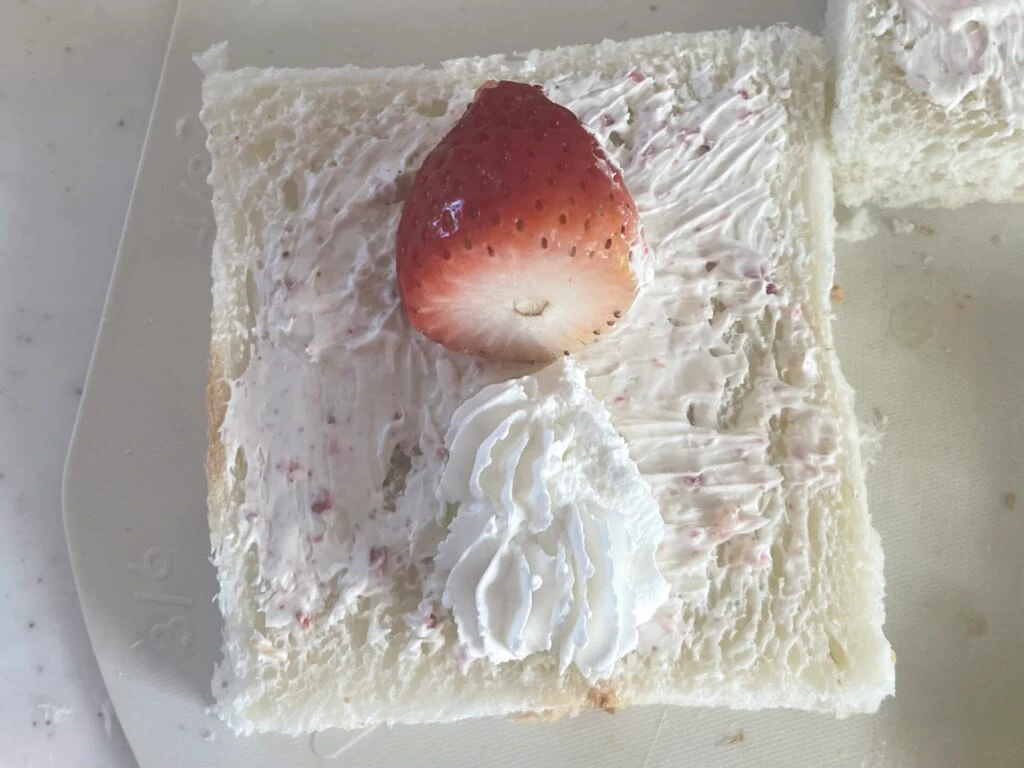 縦に並んだいちごとキウイにクリームをのせている