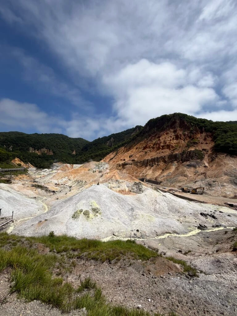 白い岩肌と噴気の上がる谷の全景