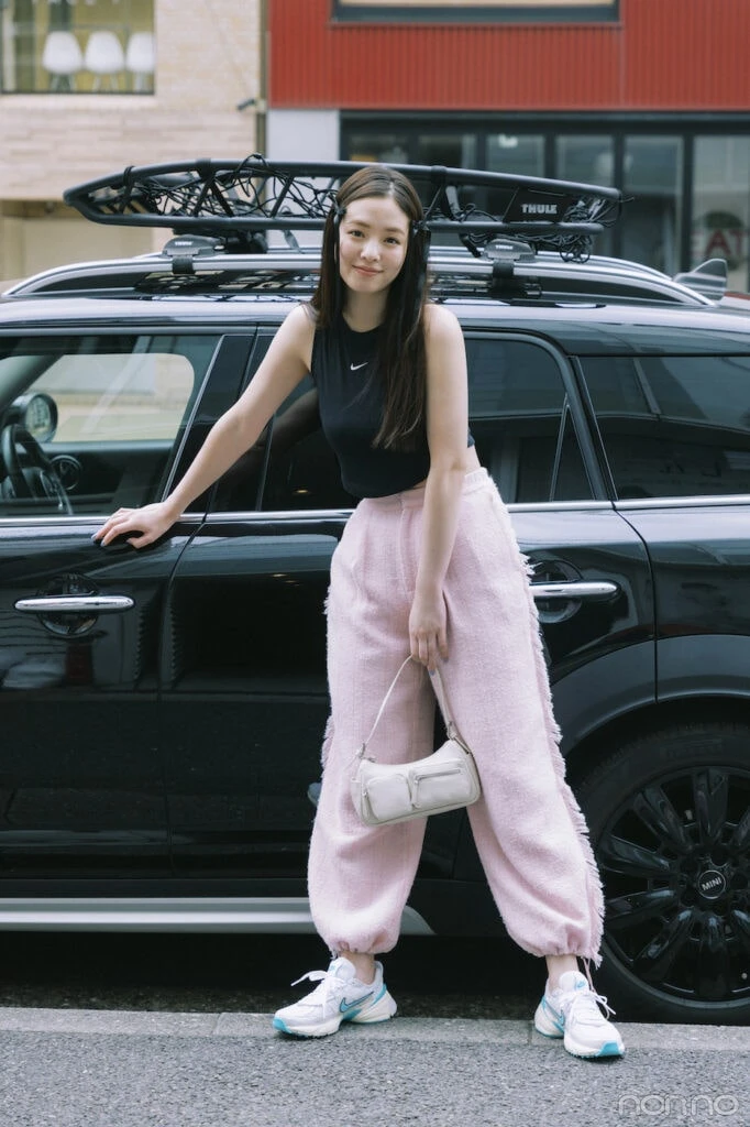 車の前に立つパンツスタイルの横田真悠