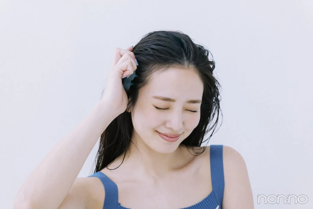こめかみに頭皮ブラシをあてる横田真悠
