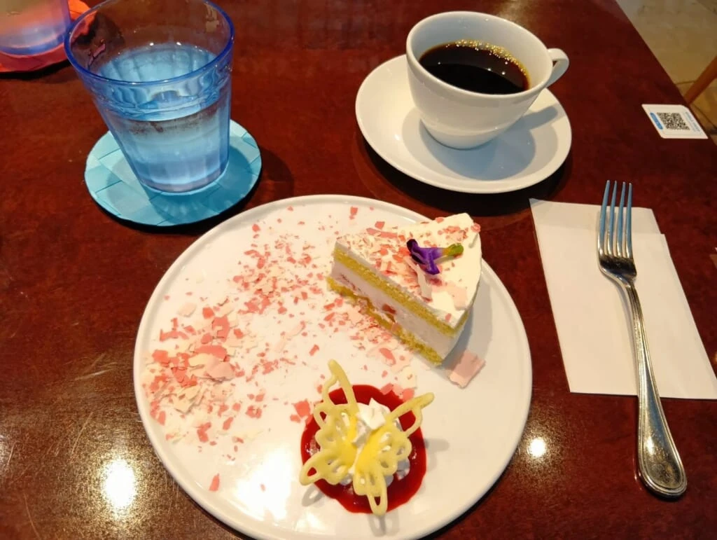 真ん中にケーキ、左に水の入ったコップ、右にコーヒー