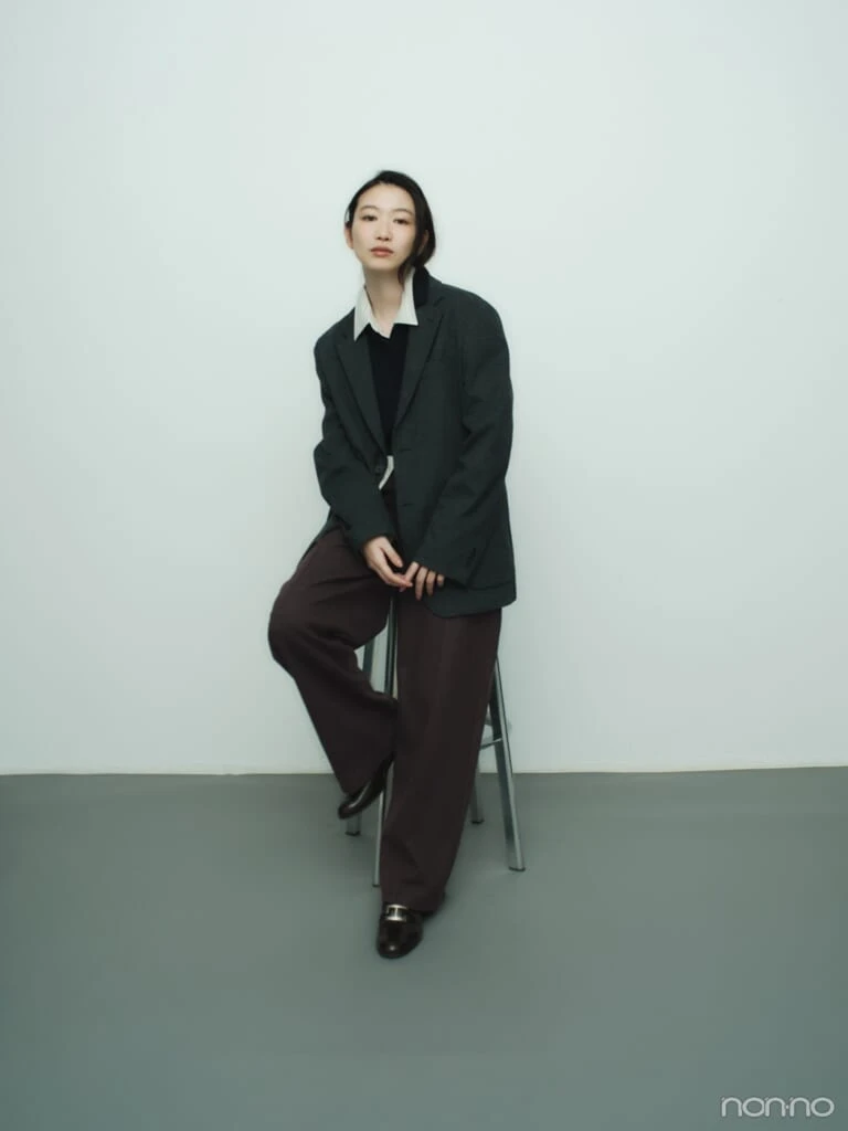 ユニクロのブラッシュドジャージーワイドパンツをオフィスカジュアル調に着こなし、椅子に座った岡本夏美の全身カット
