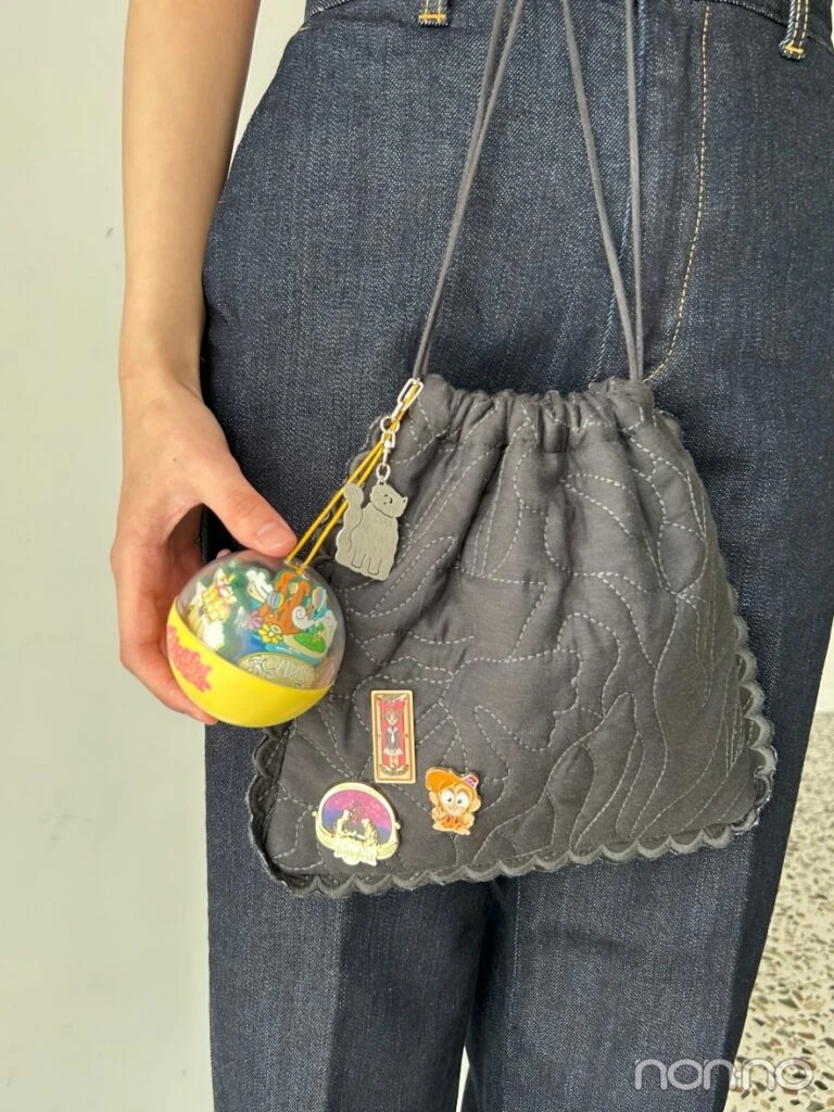キーホルダーやピンバッジのついた黒の巾着バッグ
