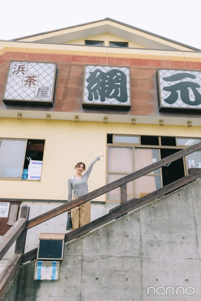 店前の階段で手を挙げる紺野彩夏