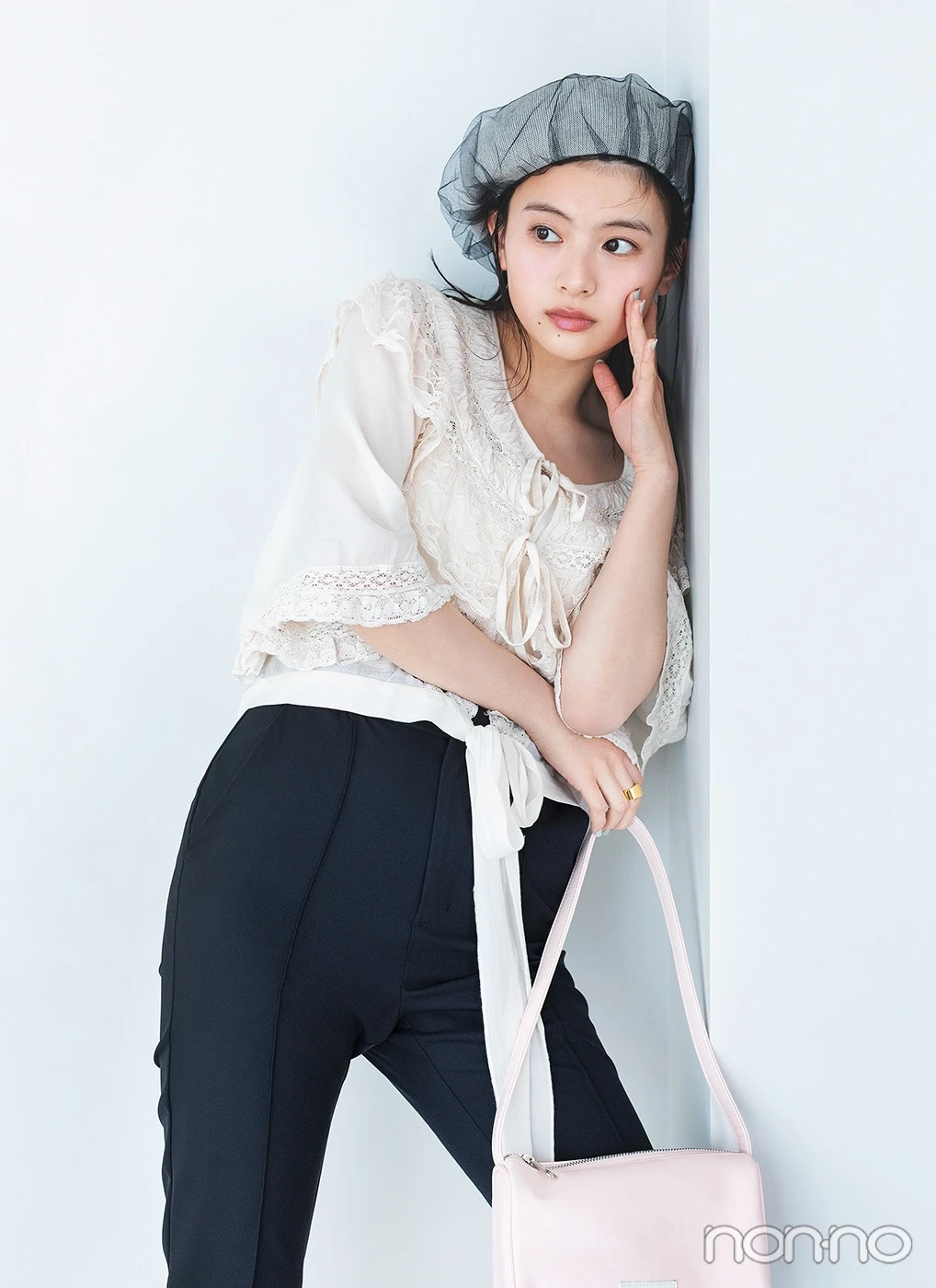 白ブラウスに黒パンツを履いて壁に寄りかかる出口夏希のアップ