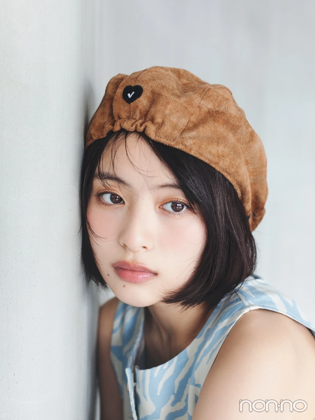 キャメルの帽子をかぶって横を向く出口夏希