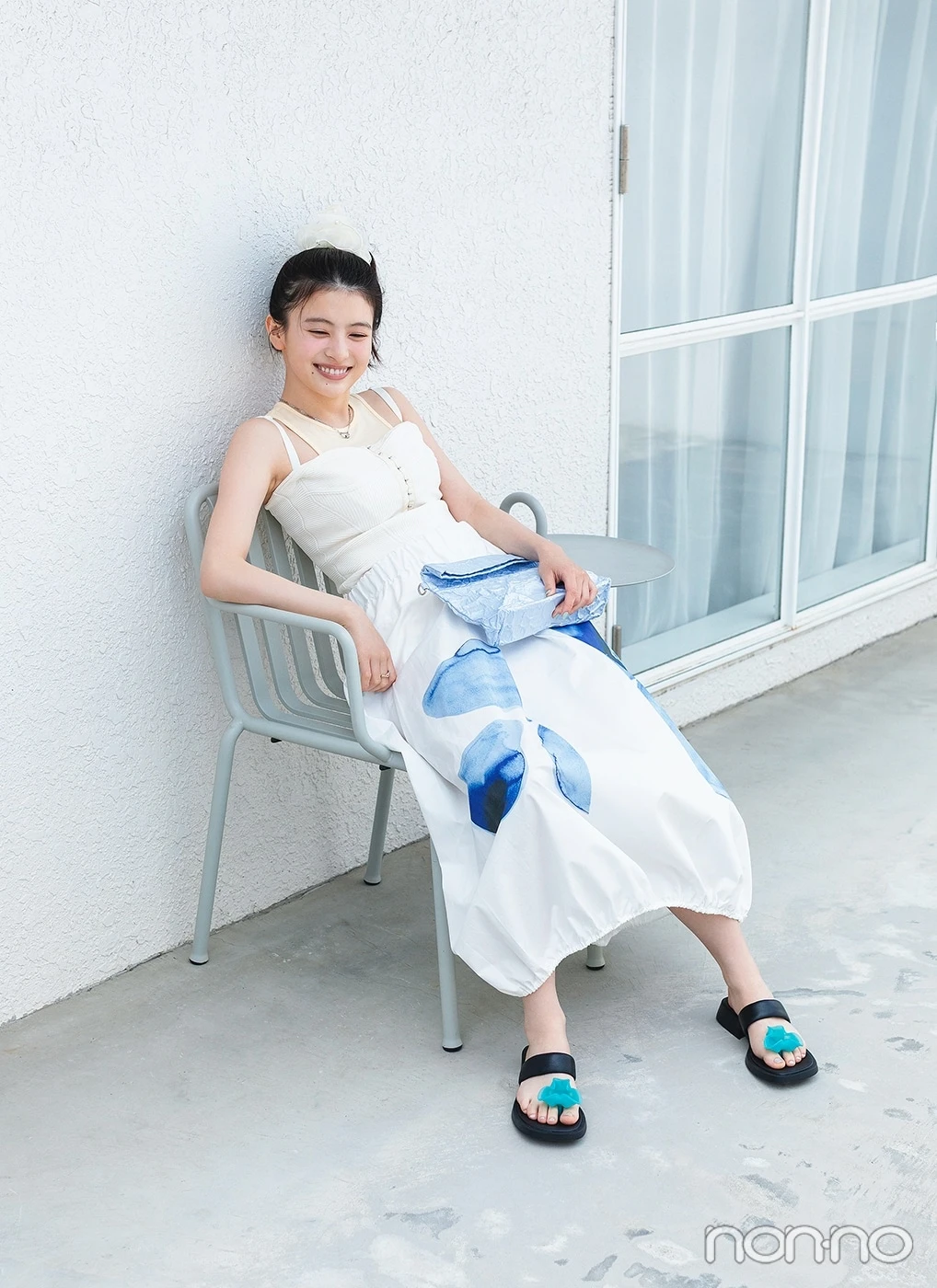 白いキャミに白いスカートを履いて椅子に座る出口夏希