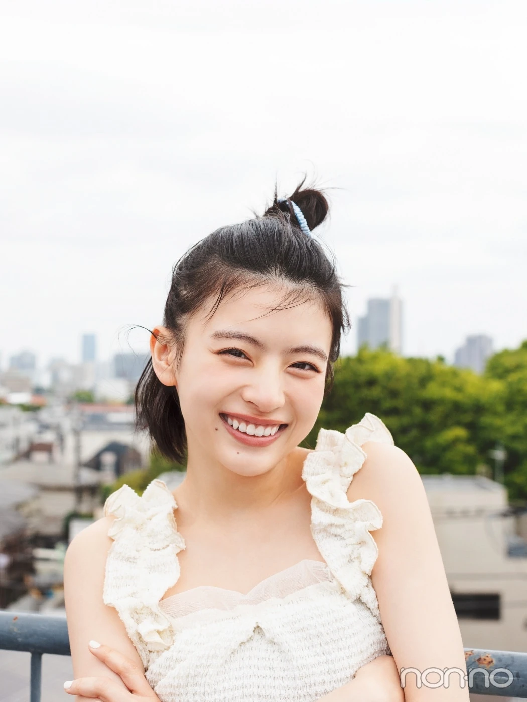 白いトップスにハーフアップヘアで笑う出口夏希