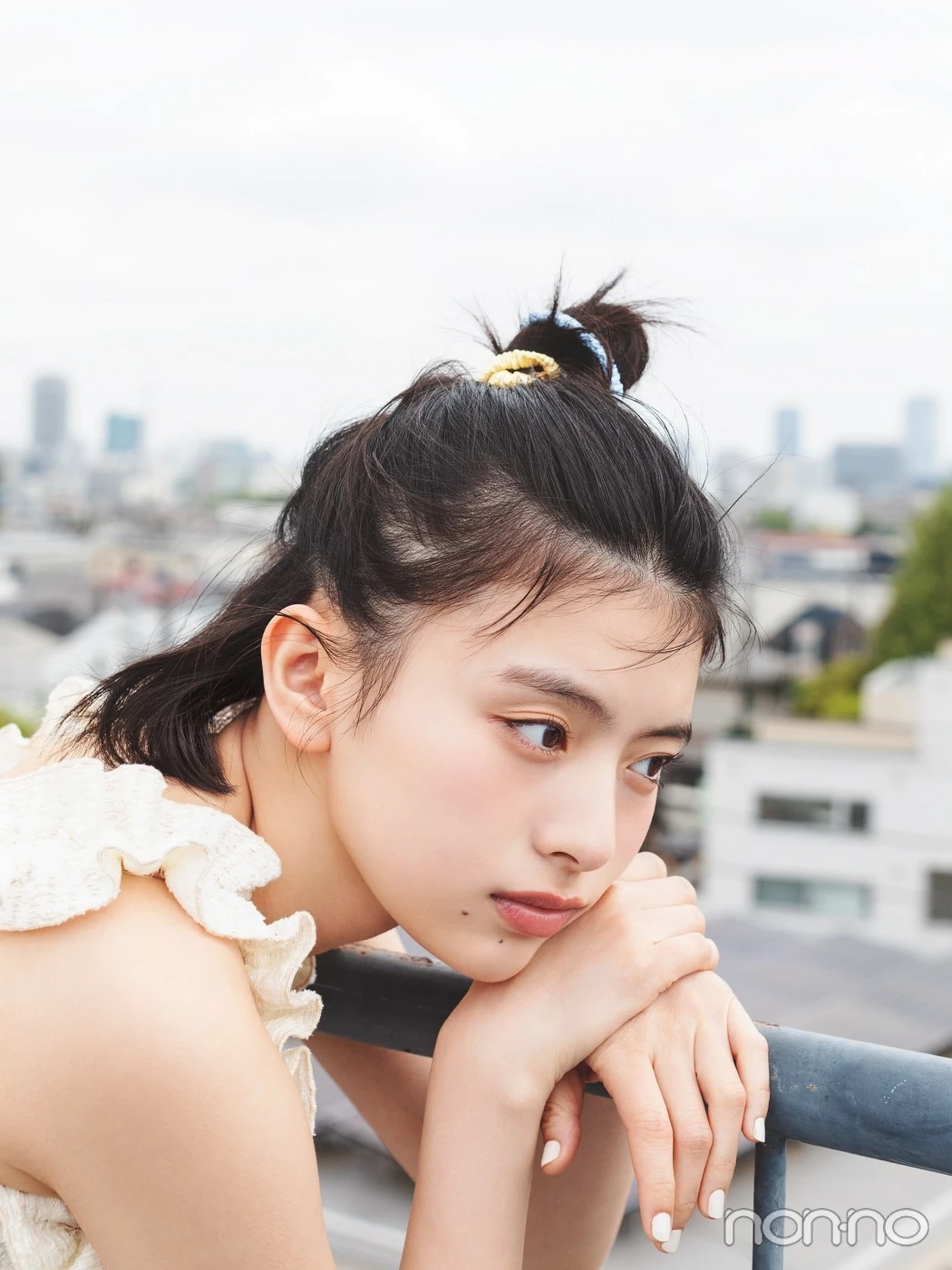 白いトップスにハーフアップヘアで手すりにもたれる出口夏希