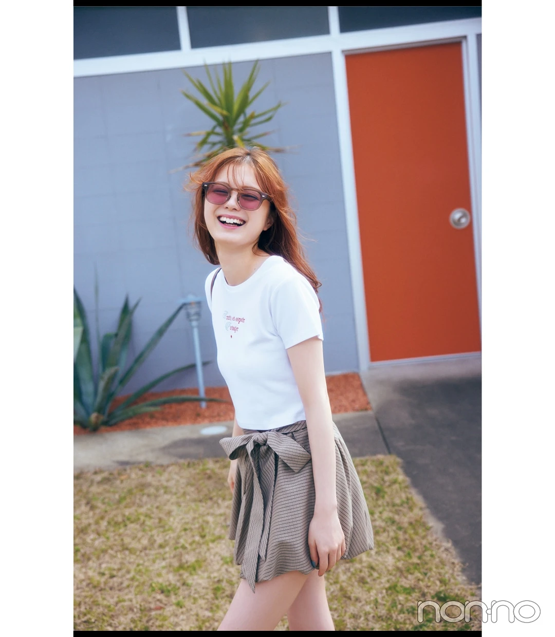 白のロゴ入りTシャツ×ミニスカコーデで歩いている女性