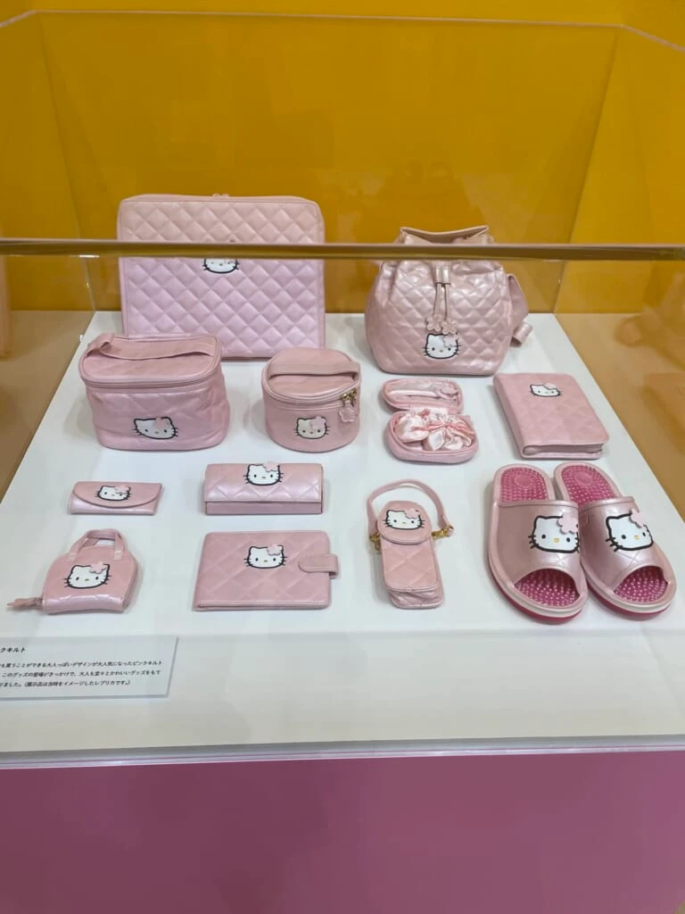 ピンク色でキルト記事のキティのグッズが並んでいる。バッグやポーチが多い。