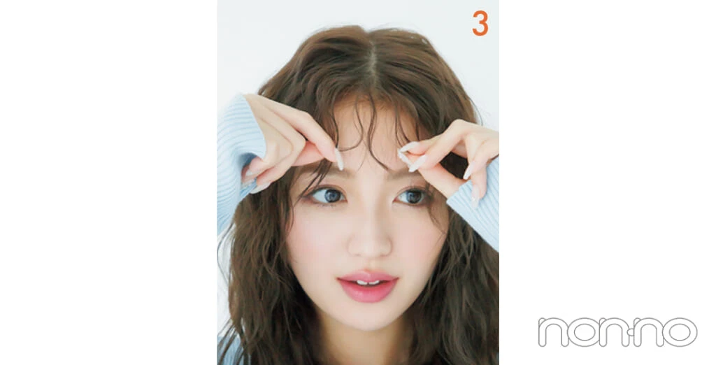 ヘアワックスをつけた指で前髪をつまんでいる女性
